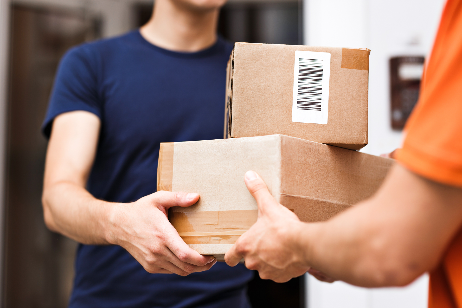 A person wearing an orange T-shirt is delivering parcels to a satisfied client.