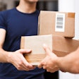 A person wearing an orange T-shirt is delivering parcels to a satisfied client.