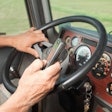 Trucker holding cellphone while behind the wheel of a semitruck