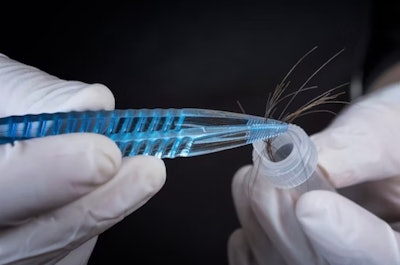 Person using tweezers to put hair sample in test tube