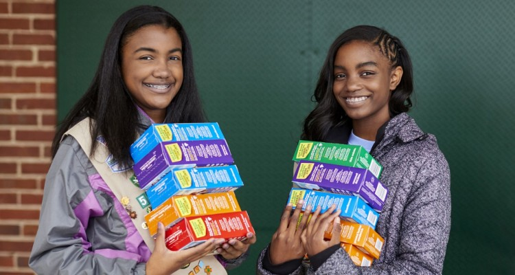 Two Girl Scouts with boxes of cookies