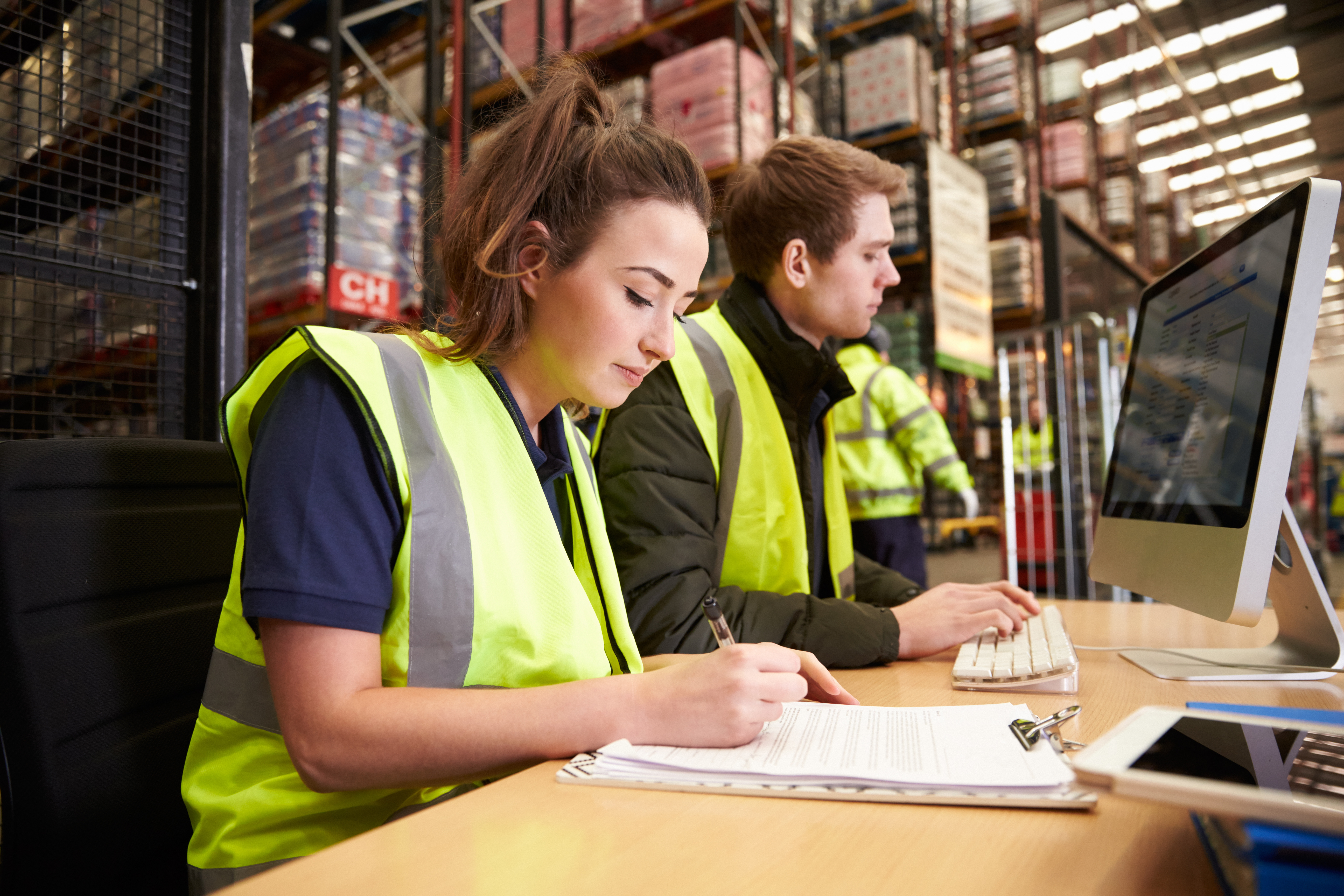 two people in a warehouse looking at a computer