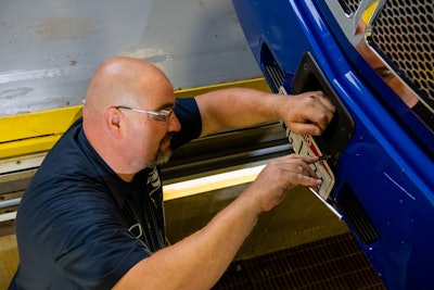 A technician adjusts an ADAS sensor on the front of a truck.