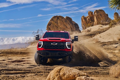 2024 chevrolet silverado hd zr2 bison stirring up dirt in desert boulders background