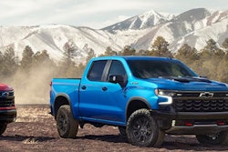 red blu white 2024 Chevy Silverado pickup trucks lined up mountain background