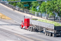 red semi truck hauling a bulk load of corn