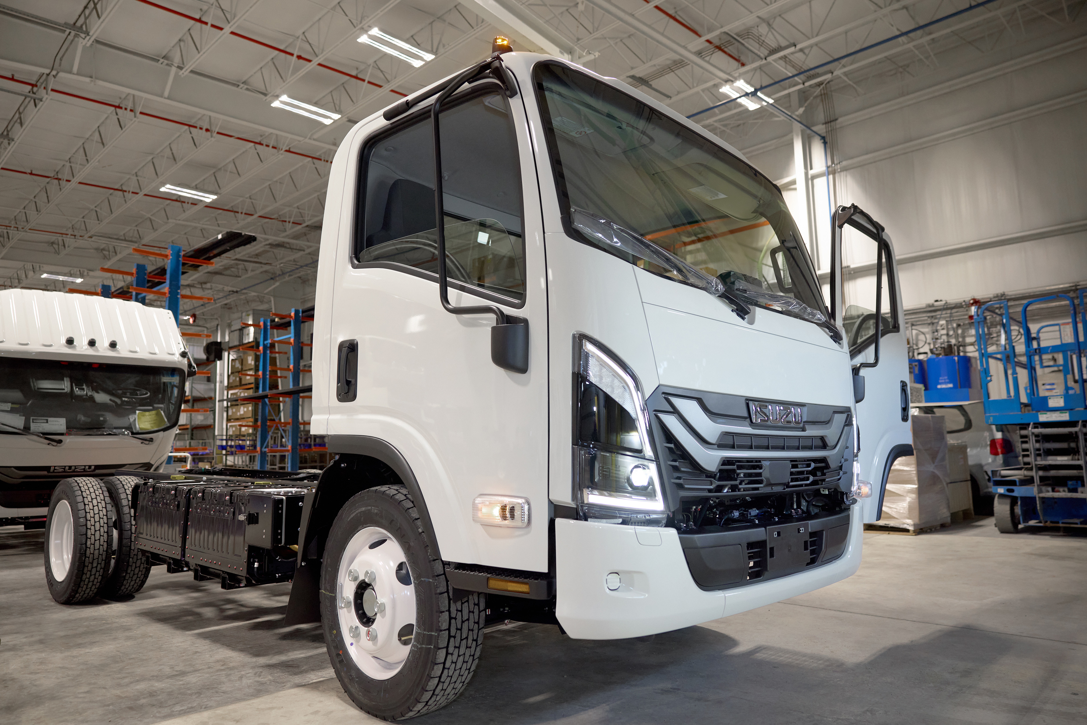 A white electric Isuzu truck on the assembly line