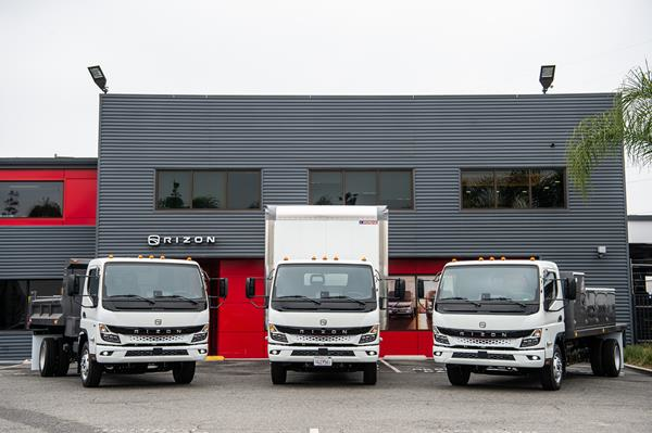 Three trucks in front of a gray metal building