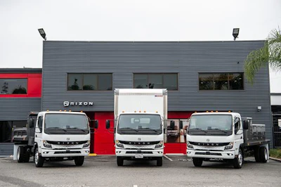 Three trucks in front of a gray metal building