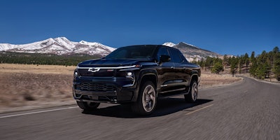 2025 dark blue 2025 Chevy Silverado EV on valley road wi snow-capped mountains background