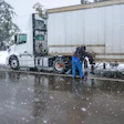 Truck driver adding chains in snow weather