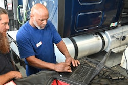Mechanics using a computer to diagnose a truck problem