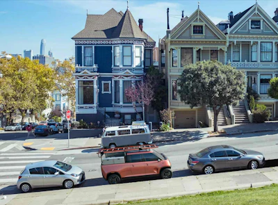 orange electric telo mt1 pickup truck parked on street across San Francisco row houses