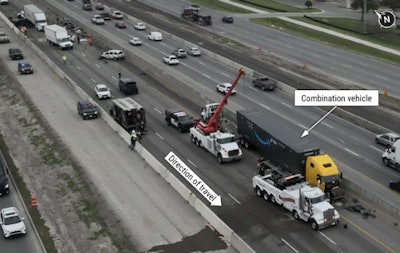 This aerial view of the crash site on I-35 shows the tractor-trailer at its final rest position. Other crash-involved vehicles can be seen within the roadway behind the combination vehicle.