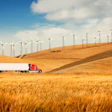 Semi truck driving alongside wind farm