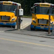 Two yellow school buses charging at electric charging stations