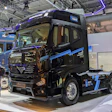 Black Scania semi-truck with blue accents displayed at industrial trade show