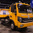 Bright yellow commercial tow truck displayed at an industry trade show