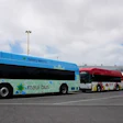 Blue and green Maui Bus electric transit buses parked at depot under cloudy sky
