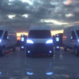 Three white electric delivery vans parked at sunset.
