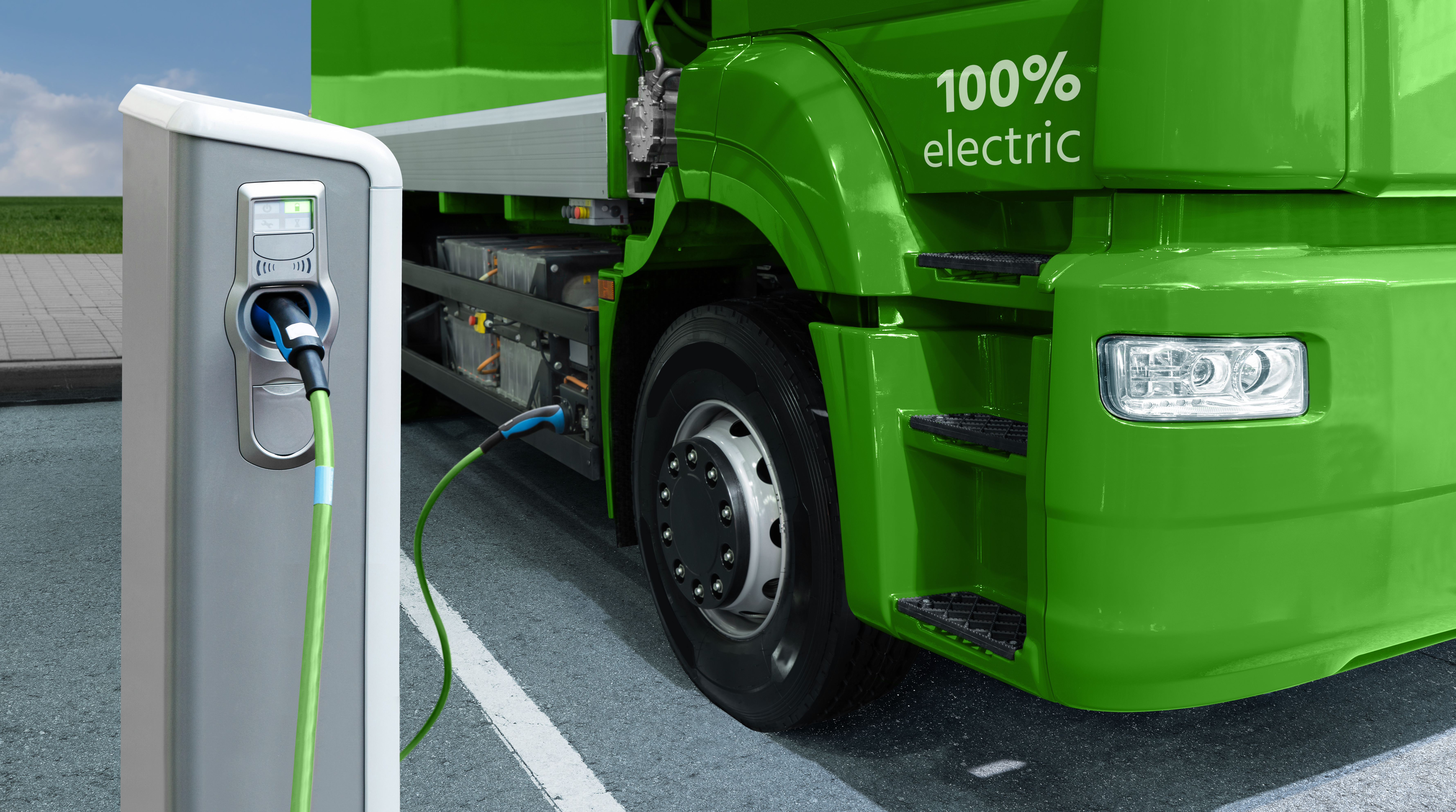 A rendering of an electric semi truck plugged in at a charging station.