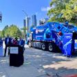 Blue Republic Services garbage truck at urban press conference with city skyline