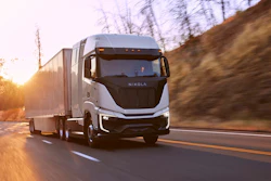 A Nikola Tre semi driving on a highway at sunset.