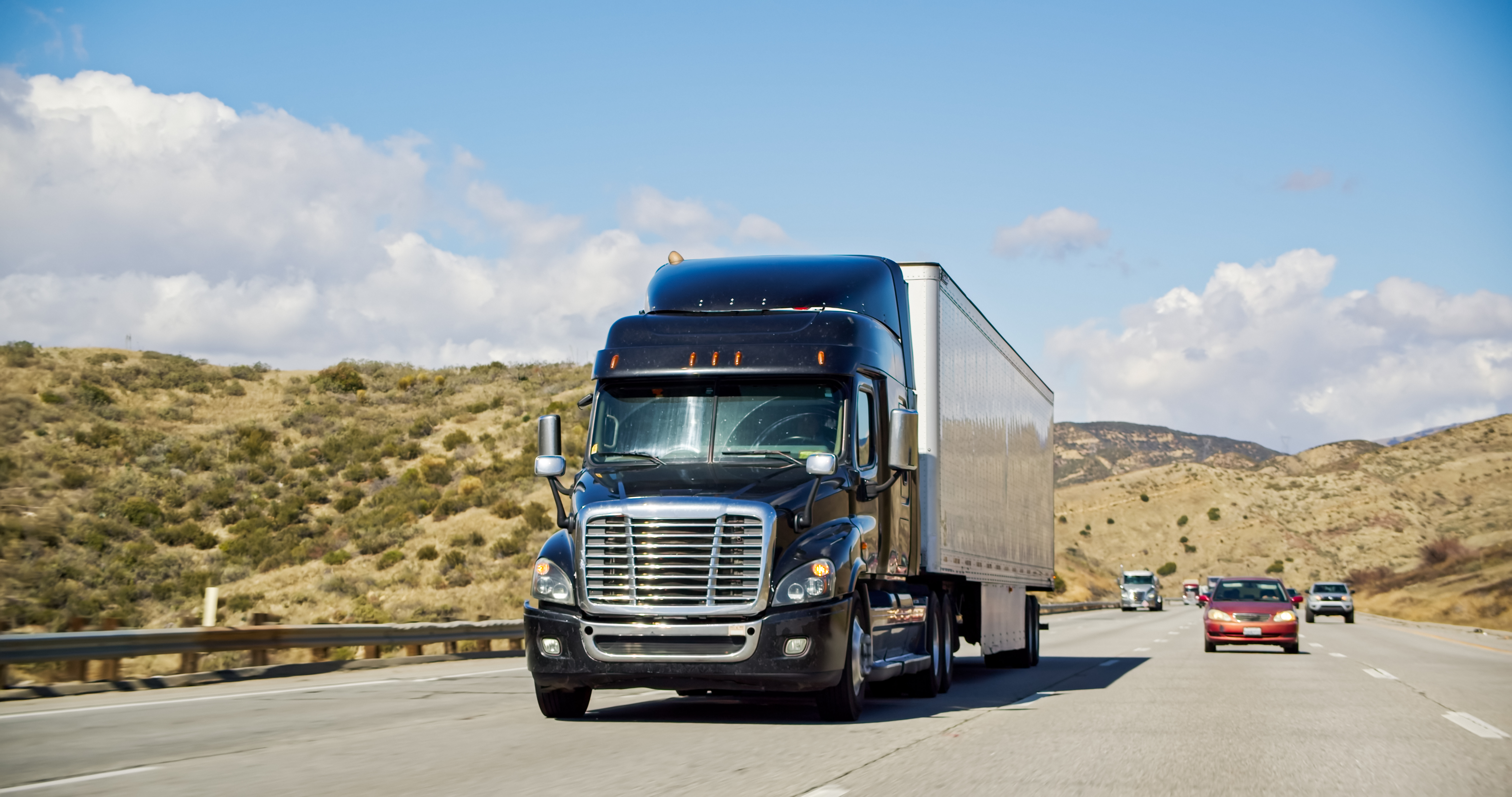 Blue Freightliner semi-truck driving on California highway