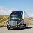 Blue Freightliner semi-truck driving on California highway