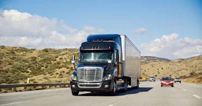 Blue Freightliner semi-truck driving on California highway