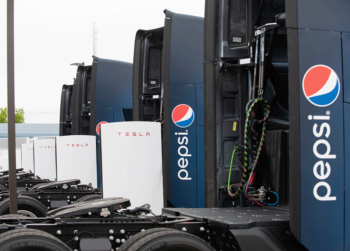 Pepsi-branded Tesla Semis parked at a charging stalls.