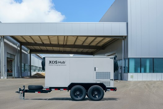 White XOS Hub trailer parked near industrial building