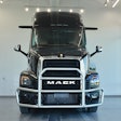 Black Mack semi-truck with chrome grille guard, front view in showroom