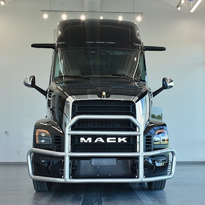 Black Mack semi-truck with chrome grille guard, front view in showroom