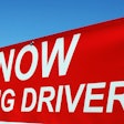 Red hiring sign advertising job openings for drivers against blue sky