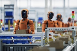 Orange industrial robots working on an automated assembly line with machinery
