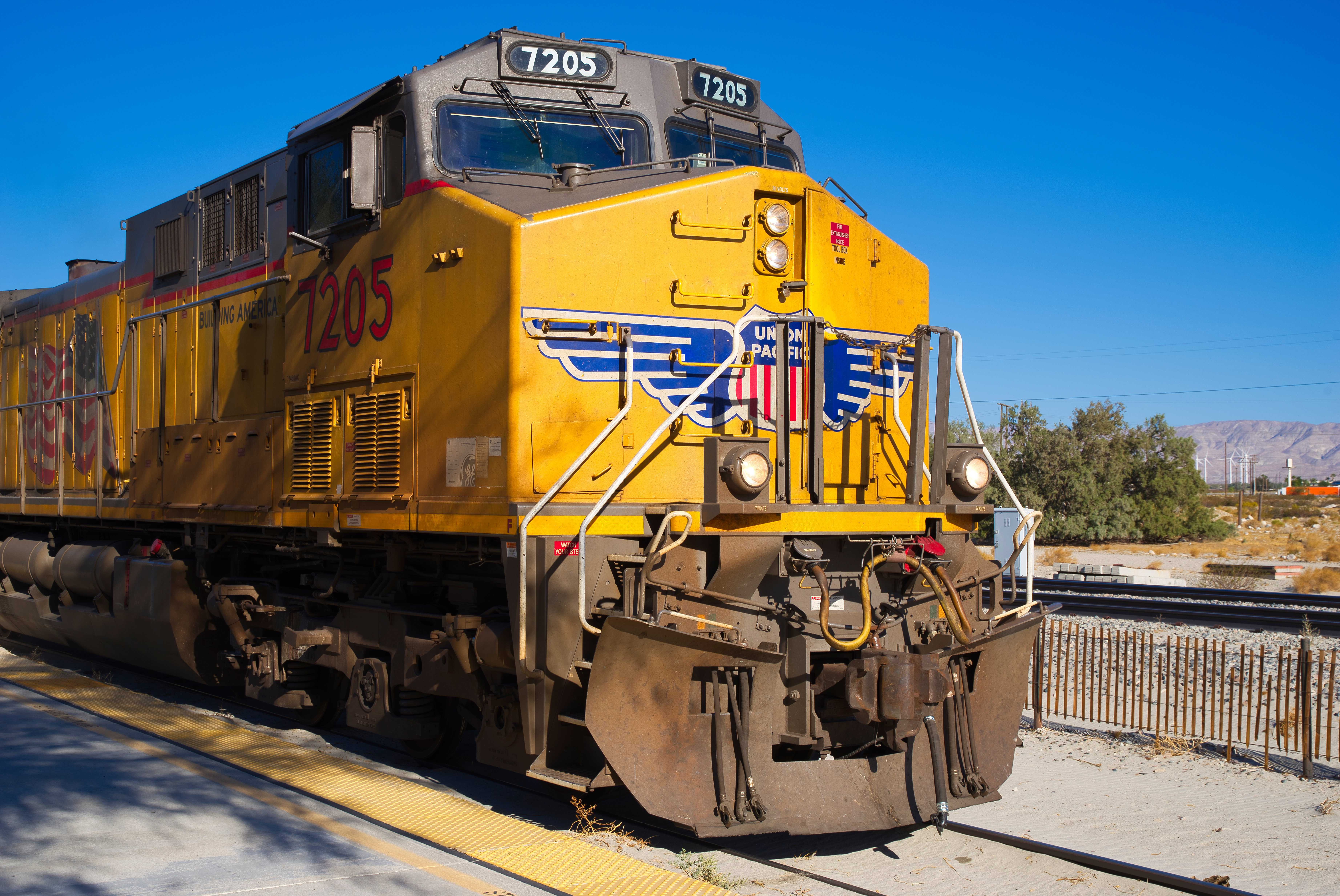 Yellow Union Pacific locomotive 7205 on railway tracks with mountains in background