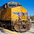 Yellow Union Pacific locomotive 7205 on railway tracks with mountains in background