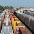 Crowded freight train yard with multiple colorful cargo containers and train cars