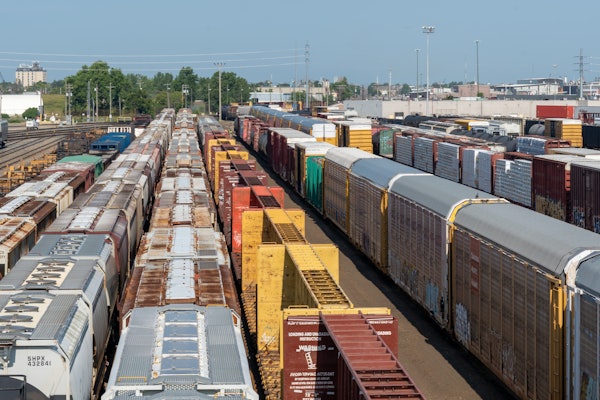 Crowded freight train yard with multiple colorful cargo containers and train cars