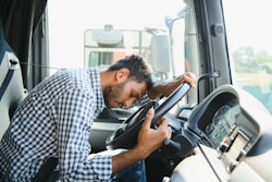 Truck driver asleep at steering wheel in blue checkered shirt