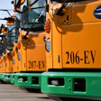 Row of yellow Blue Bird electric school buses with green trim