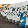 White and blue semi-trucks lined up in a row with mountainous landscape in background