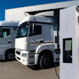 White semi-trucks parked at electric charging station with blue sky background