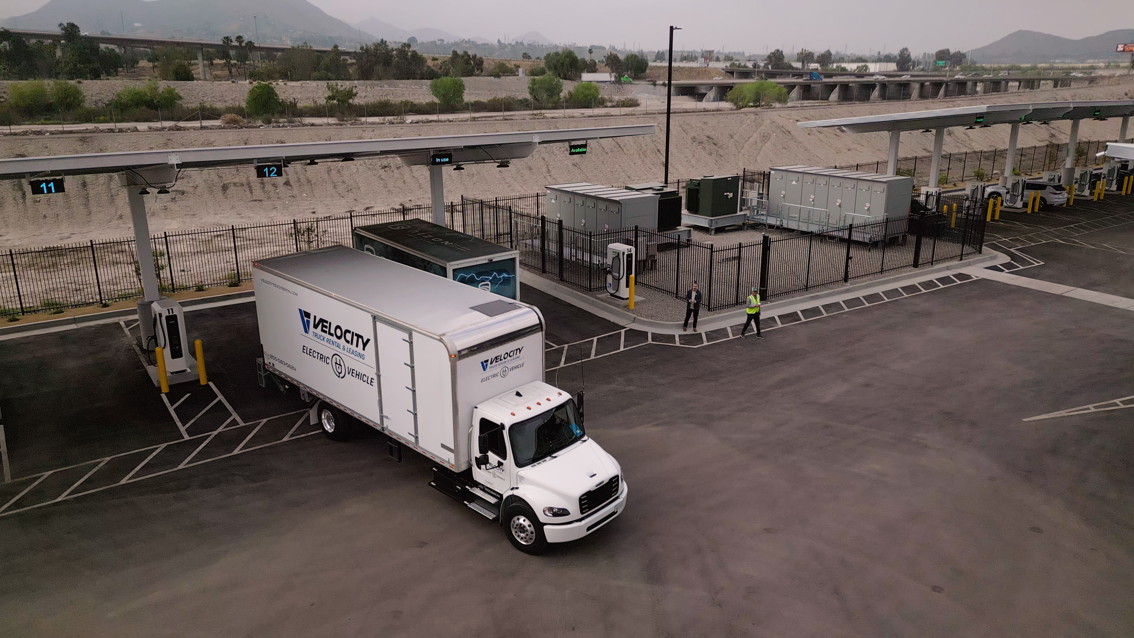 A truck from Velocity Truck Centers is show pulling out of an Greenlane EV charging terminal.