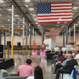 ZM Trucks event with CEO on stage speaking to audience seated in industrial warehouse with American flags