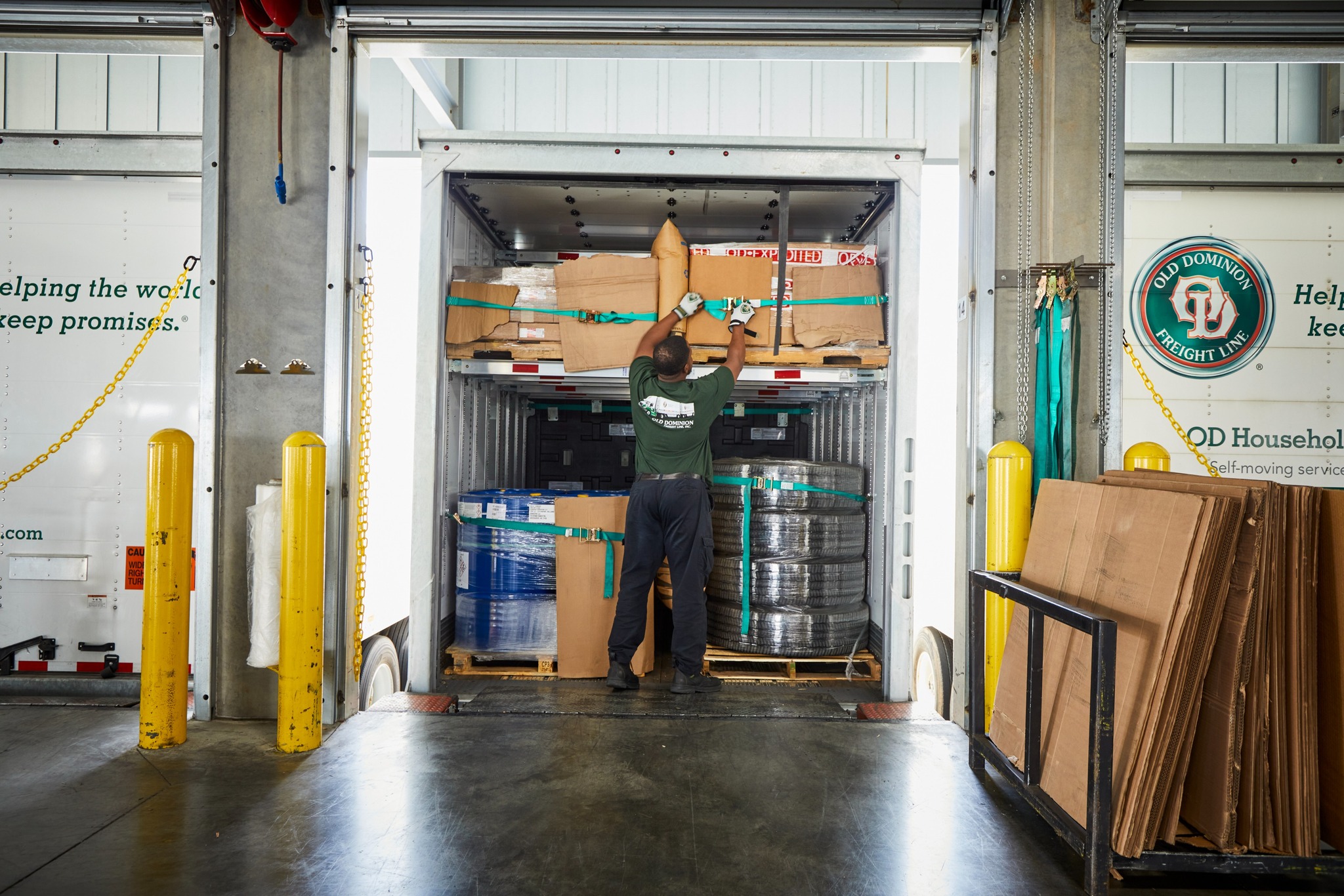 Warehouse worker loading boxes and metal coils into a shipping container