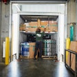 Warehouse worker loading boxes and metal coils into a shipping container