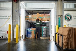 Warehouse worker loading boxes and metal coils into a shipping container