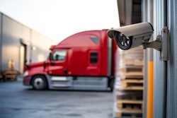 Security camera overlooking red semi-truck at warehouse loading dock